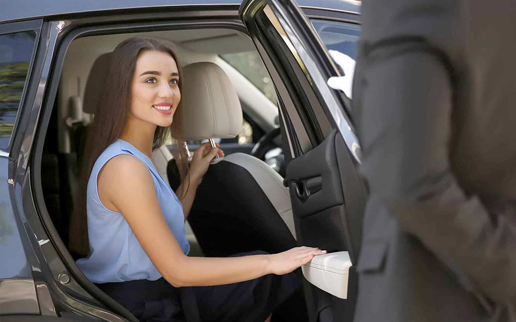 Driver open car door for a young businesswoman